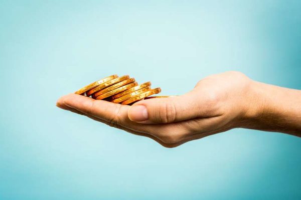 Hand holding golden coins concept on blue background. Business concept.